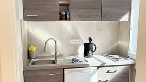 A compact kitchen with a built-in dishwasher, a coffee maker, and a sink. - Apartment "Prague" (Korschenbroich)
