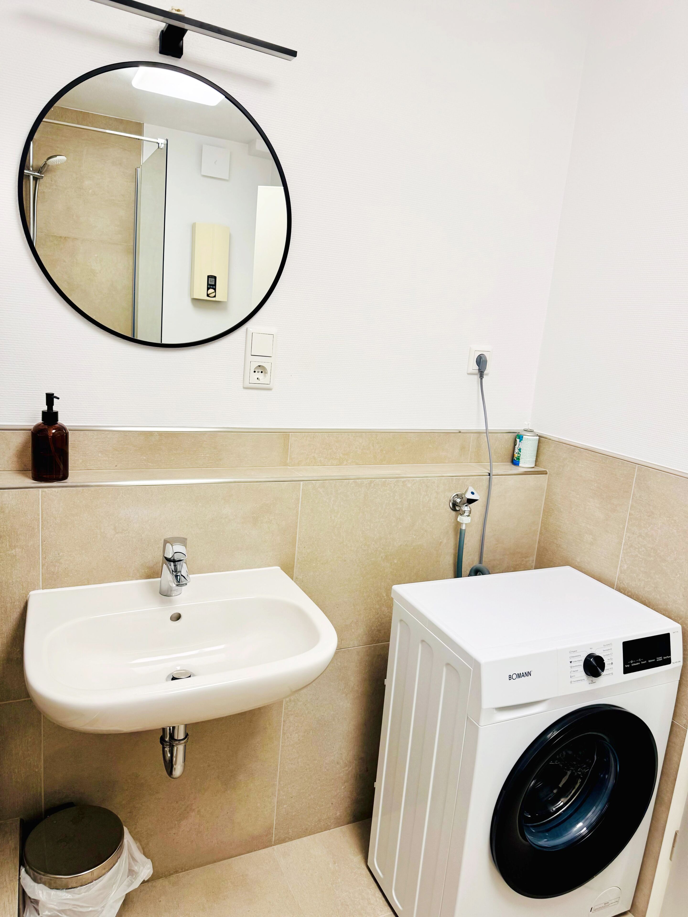 Une salle de bain équipée d’un lavabo, d’un miroir et d’un lave-linge.