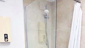 A glass-enclosed shower with a handheld showerhead, a white toilet, and a towel rack. - Apartment "Prague" (Korschenbroich)