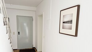A hallway with a door, a doormat, and a framed picture on the wall. - Apartment "Prague" (Korschenbroich)