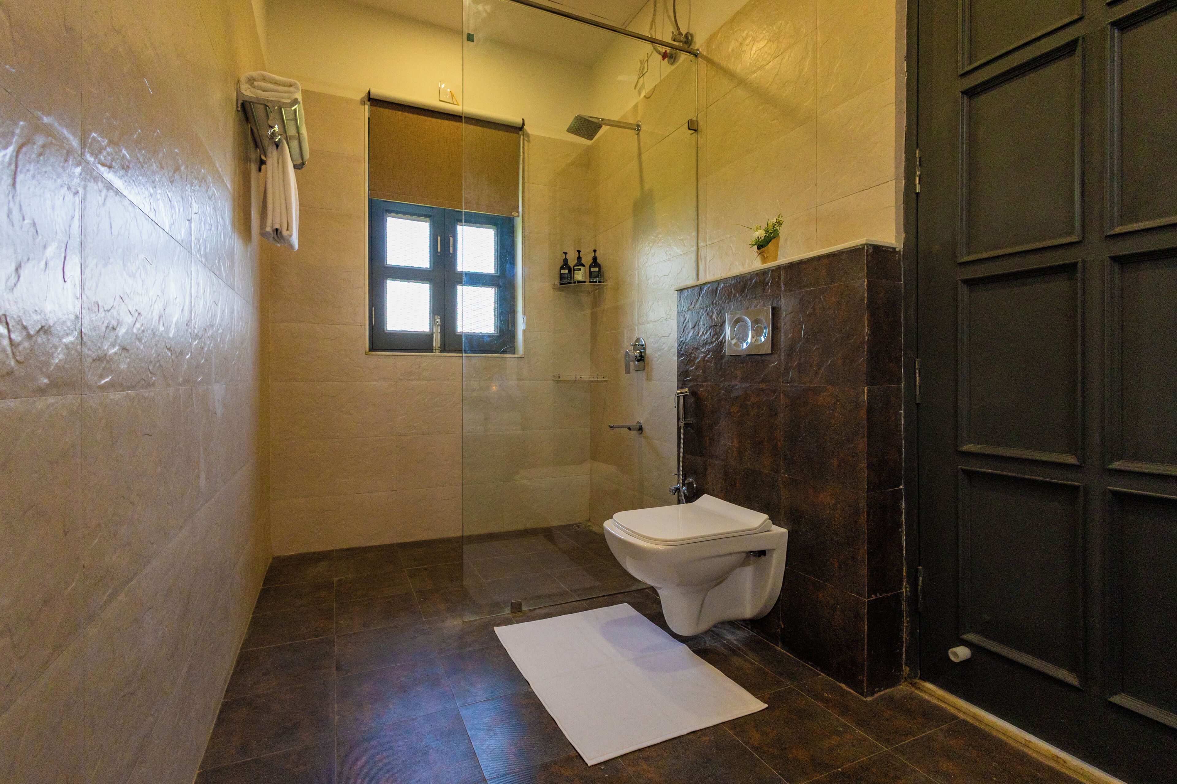 Een badkamer met een douche, toilet en een raam.
