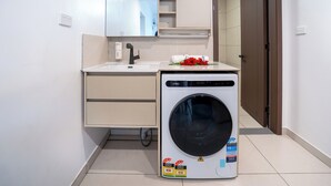 Ein kleines Badezimmer mit Waschbecken, Spiegel und einer Waschmaschine mit Frontlader.