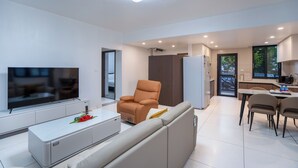 Ein modernes Wohnzimmer mit Flachbildfernseher, Sofa und Couchtisch.