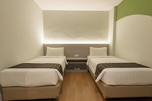 Habitación doble con dos camas, un estante pequeño y un par de pantuflas.