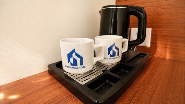 Two white mugs with a hotel logo on a tray with a coffee maker. - Inn Room Hotel Bajo (Labuan Bajo)
