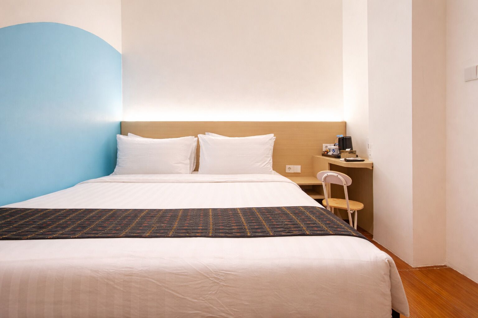 A hotel room with a bed, a chair, a desk, and a nightstand.