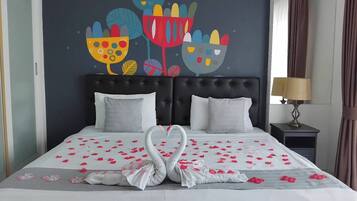 Un letto decorato con petali di rosa e cigni, un quadro con colori vivaci e una lampada su un comodino.