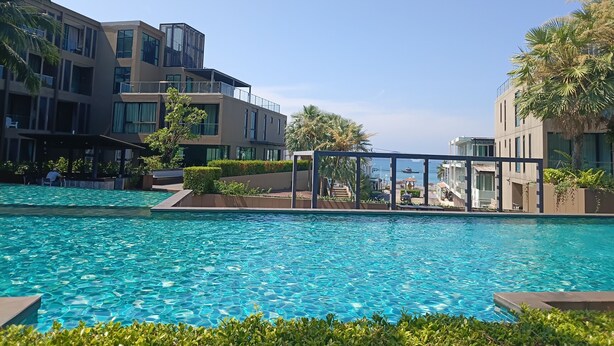 A swimming pool with clear water, surrounded by modern buildings and palm trees. - Sea Panwa Beach (Wichit)