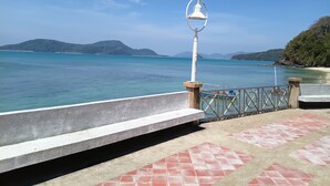 A coastal walkway with a metal railing, a white lamp post, and a bench. - Sea Panwa Beach (Wichit)