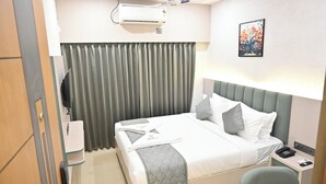 Habitación de hotel con cama, escritorio con teléfono, aire acondicionado de pared y un cuadro.