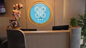 Un mostrador de recepción con un logotipo, un jarrón de flores y una planta en maceta.