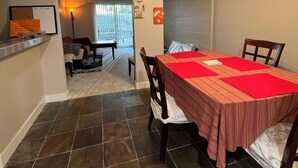 Comedor con mesa dispuesta para cuatro, ventilador de techo y vista al salón.