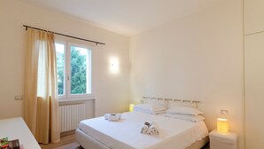 Un dormitorio limpio y minimalista con una cama grande, lámparas de noche y vistas al exterior.