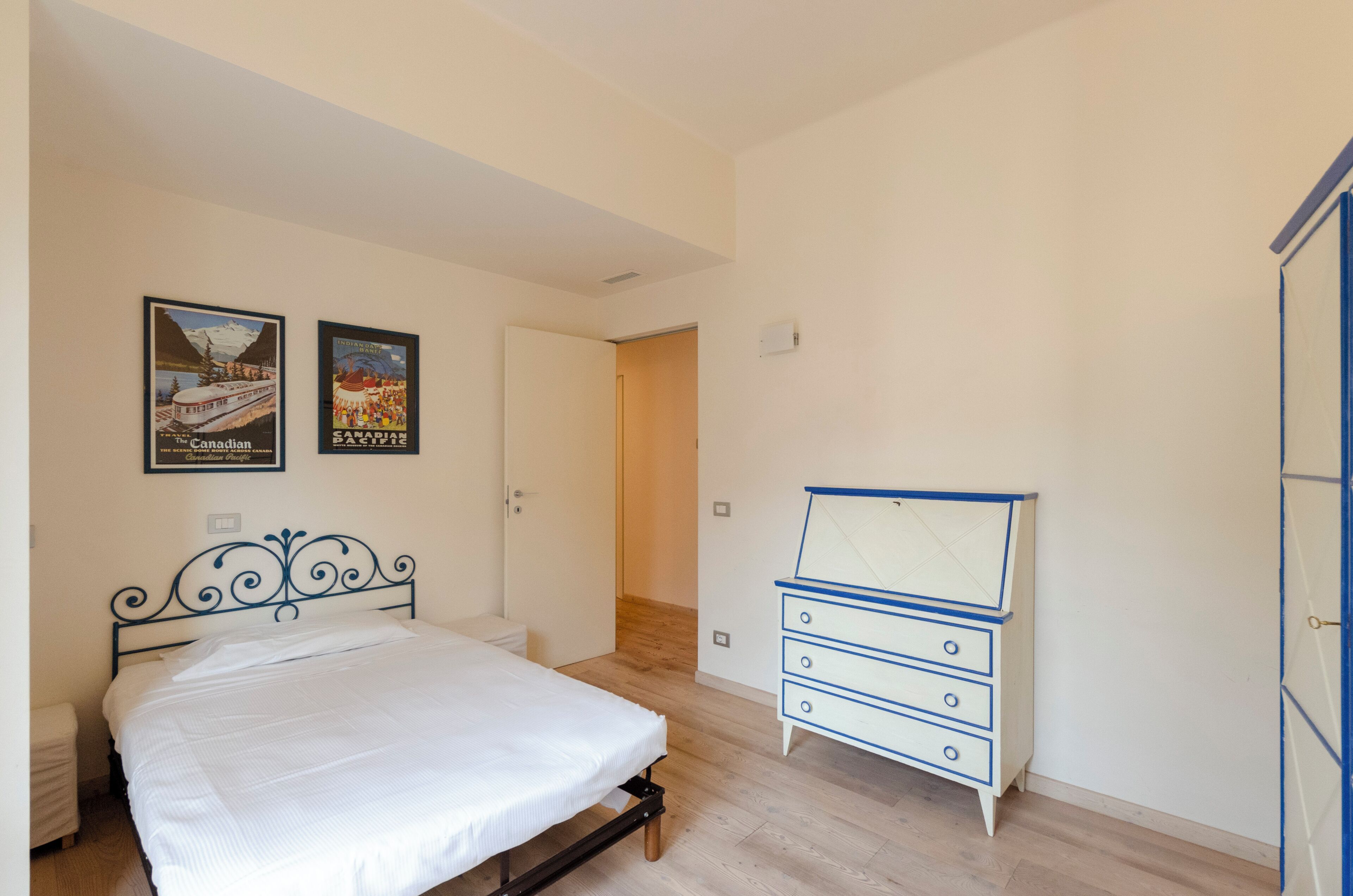 A bedroom with a bed, a dresser, and two posters on the wall.