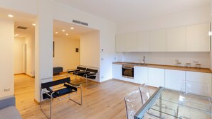 Una cocina moderna con armarios blancos, horno de acero inoxidable y una mesa de comedor de vidrio.