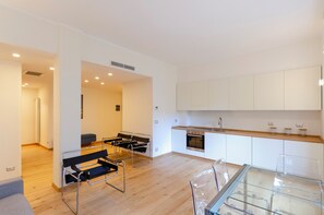A modern kitchen with white cabinets, a stainless steel oven, and a glass dining table. - 2 Flats Combined Spacious Family Retreat (Santa Margherita Ligure)
