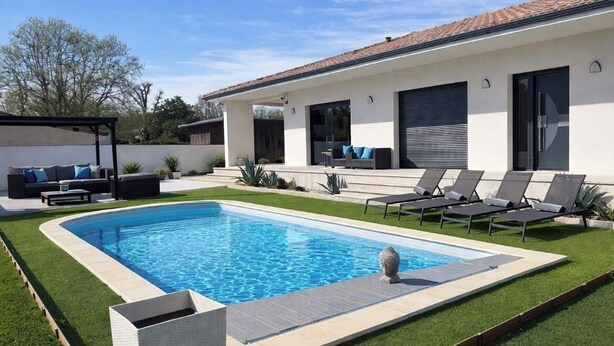 Ein modernes Haus mit Schwimmbad, Außenbereich mit Sitzgelegenheiten und einer überdachten Terrasse.