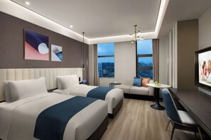 A hotel room with two beds, a sofa, a TV, and a city view.
