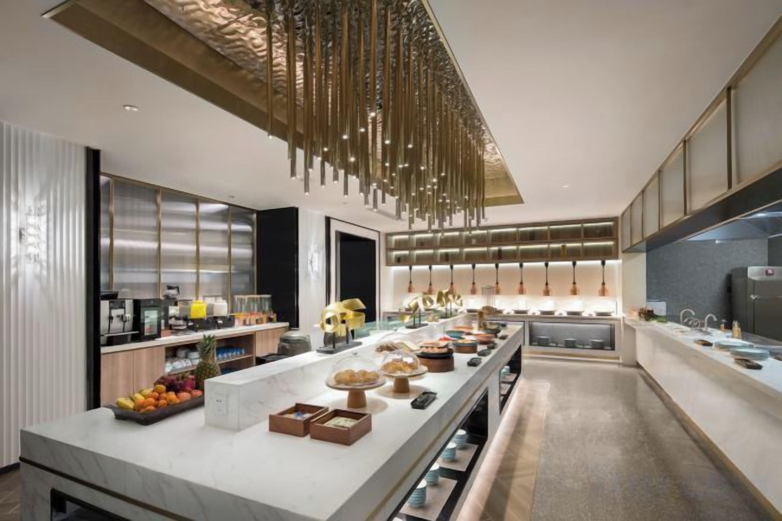 Cozinha moderna com ilha central grande, eletrodomésticos de aço inoxidável e luminária pendente.