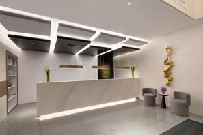 A reception area with a marble counter, modern lighting, and two grey armchairs. - Shanghai Citadines Hotel (Lujiazui Financial District Beiyangjing Road Subway Station Branch) (Shanghai)