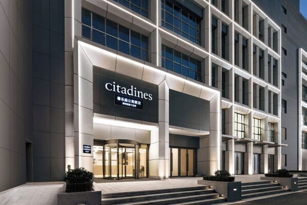 A modern building with a prominent 'Citadines' sign, large windows, and a well-lit entrance.