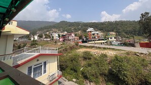A residential area with buildings, a road, and a hilly backdrop. - 555 Home Stay and Restaurant (Burhanilkantha)