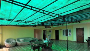 An indoor space with a patterned floor, a table with chairs, bean bags, and a ceiling with a grid structure. - 555 Home Stay and Restaurant (Burhanilkantha)