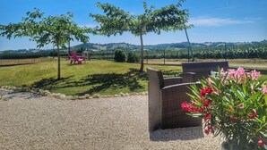 Eine Terrasse mit Gartenmöbeln, ein Kiesweg und Blick auf einen Weinberg.