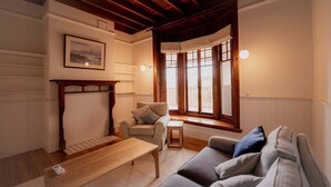 Ein gemütliches Wohnzimmer mit Kamin, einer Couch, einem Sessel und einem Fenster mit Blick.