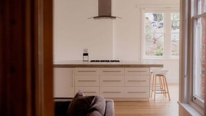 Eine moderne Küche mit einer zentralen Kochinsel, weißen Schränken und einem Fenster mit Blick auf einen Garten.