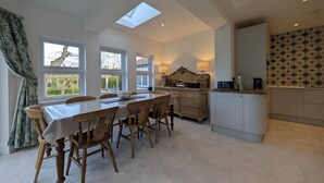 Un coin repas avec une table et des chaises, une cuisine équipée d’une cuisinière et une lucarne.