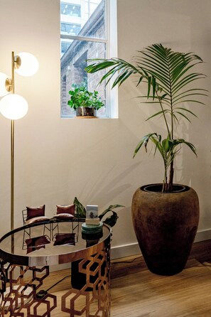 Ein Zimmer mit einer großen Topfpflanze, einem runden Tisch mit Stühlen und einer Stehlampe.