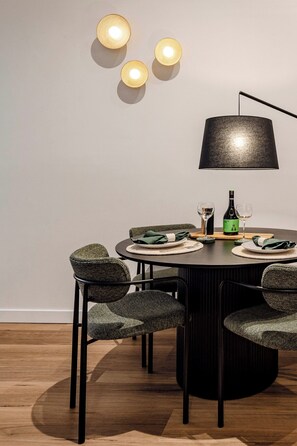 A dining area with a round table, four chairs, a lamp, and a bottle of wine. - The 'Gordon House' Prestige Experience (Melbourne)