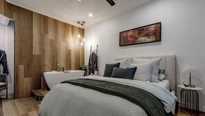 A modern bedroom with a large bed, a built-in bathtub, and a wall-mounted abstract painting. - The 'Gordon House' Prestige Experience (Melbourne)