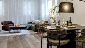 A modern living room with a dining area, featuring a sofa, a coffee table, and a dining table set for four. - The 'Gordon House' Prestige Experience (Melbourne)