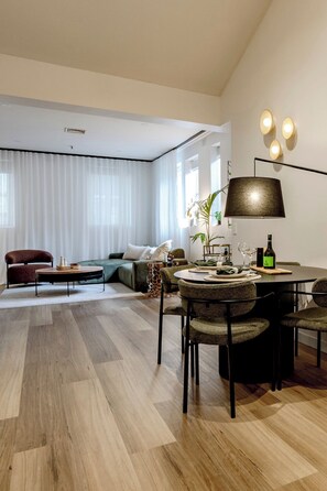 Ein modernes Wohnzimmer mit Essbereich, ausgestattet mit einer Couch, einem Couchtisch und einem Esstisch für vier Personen.