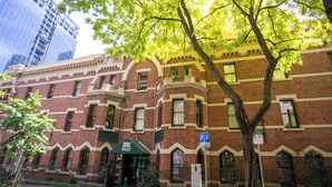 A multi-story brick building with a green awning, a parking sign, and a tree in front. - The 'Gordon House' Prestige Experience (Melbourne)