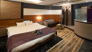 A modern hotel room with a large bed, a seating area, a small table with flowers, and a reception desk. - Hotel Bvljua -leisure hotel- Adults Only (Kurume)