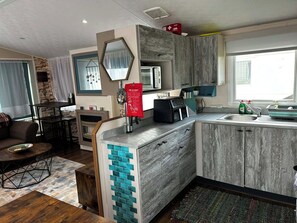 A modern kitchen with a microwave, a fire blanket, and a sink. - Lovely and Comfy 3-Bedroom Mobile Home Retreat in Kirkcolm (Kirkcolm)