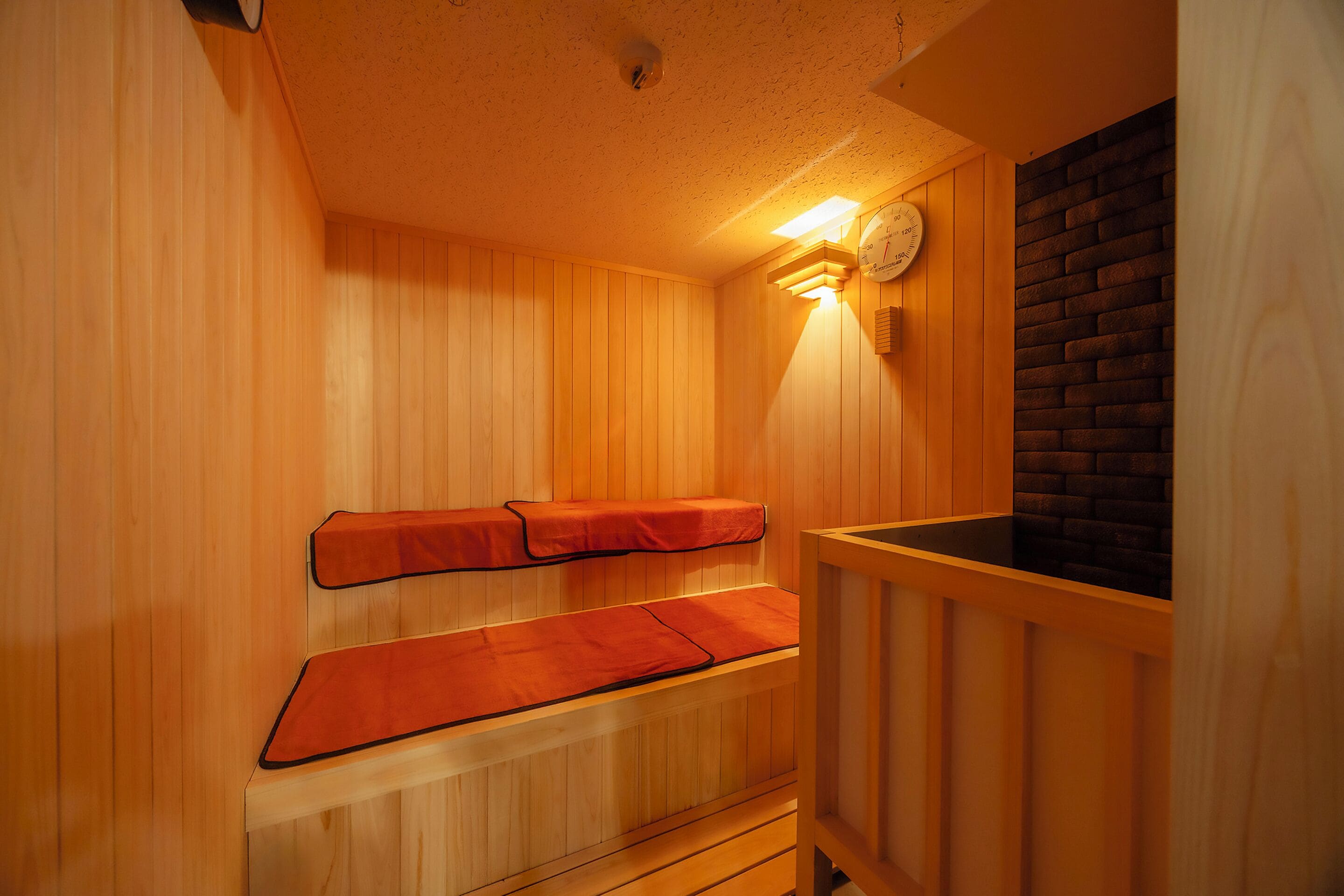 A sauna with wooden benches and a brick wall.