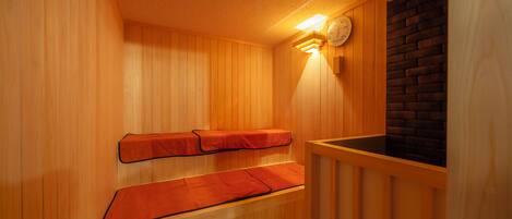 A sauna with wooden benches and a brick wall.