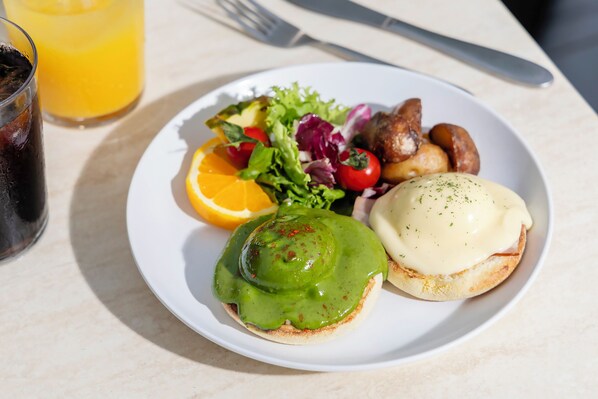 A plate with a sandwich, salad, and a glass of orange juice.