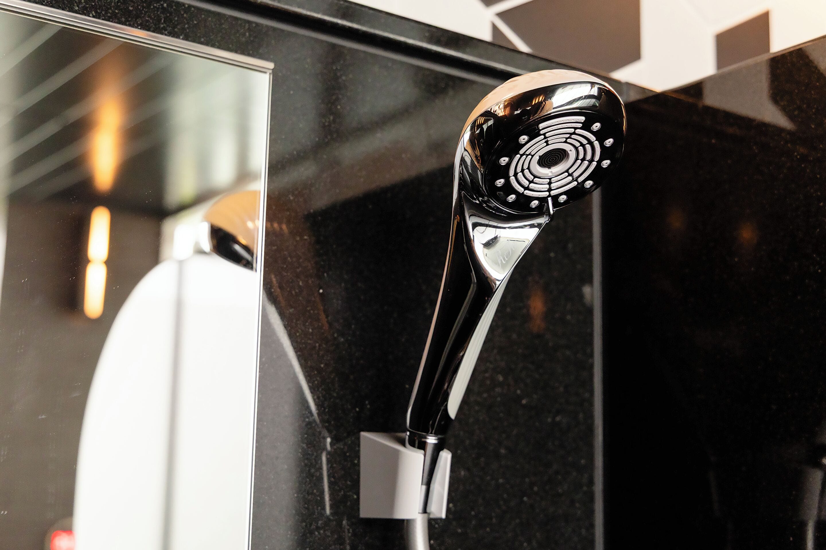 A modern, sleek showerhead with a circular design, attached to a chrome fixture.