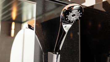 A modern, sleek showerhead with a circular design, attached to a chrome fixture.