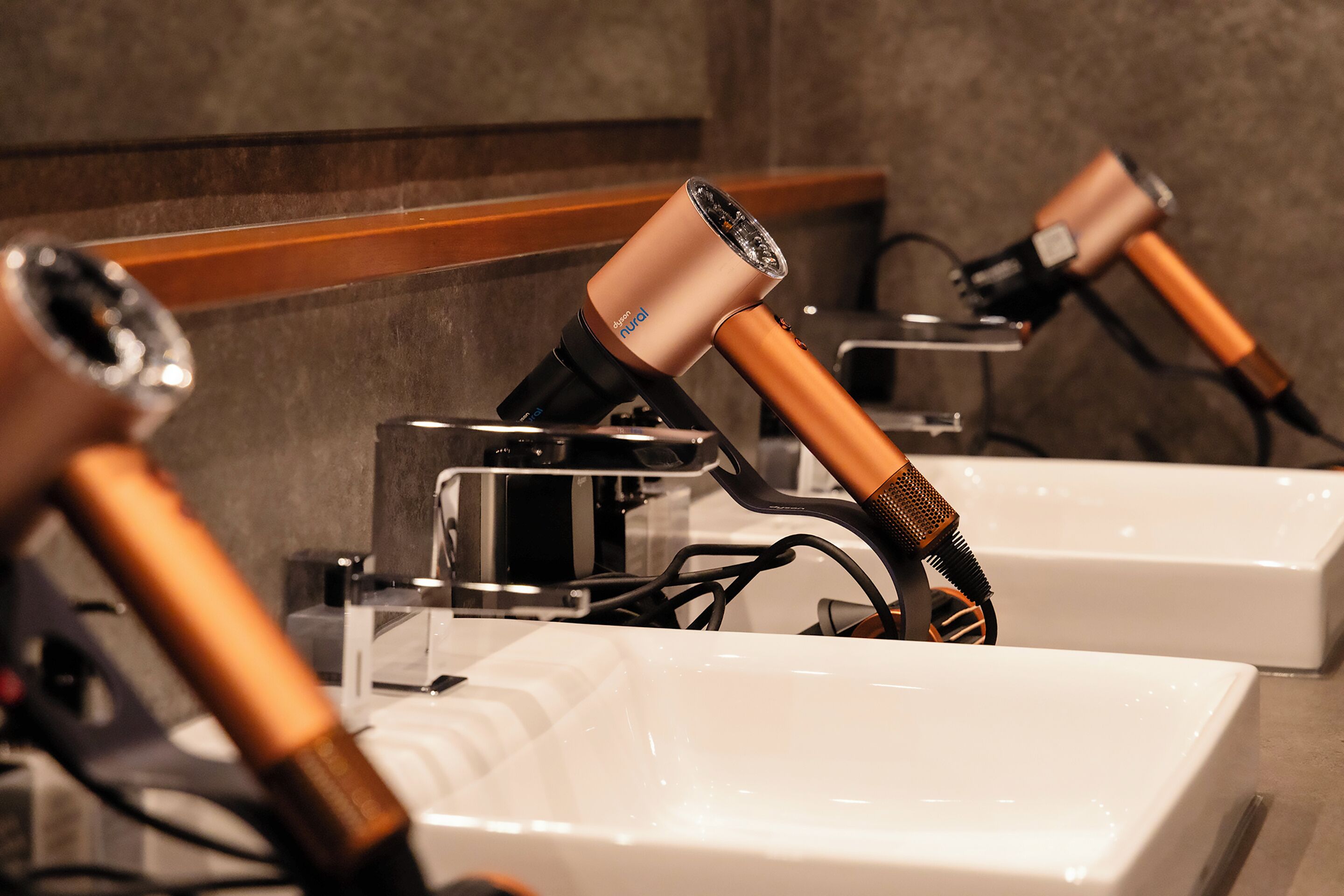 A bathroom with a white sink, a mirror, and a hairdryer mounted on the wall.