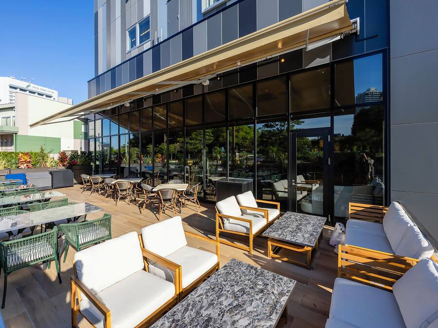 Un'area patio esterna con posti a sedere, tavoli e una struttura in vetro.