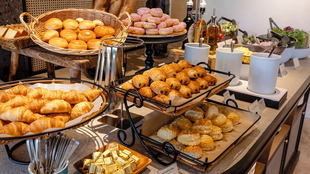 A buffet with various baked goods and condiments.