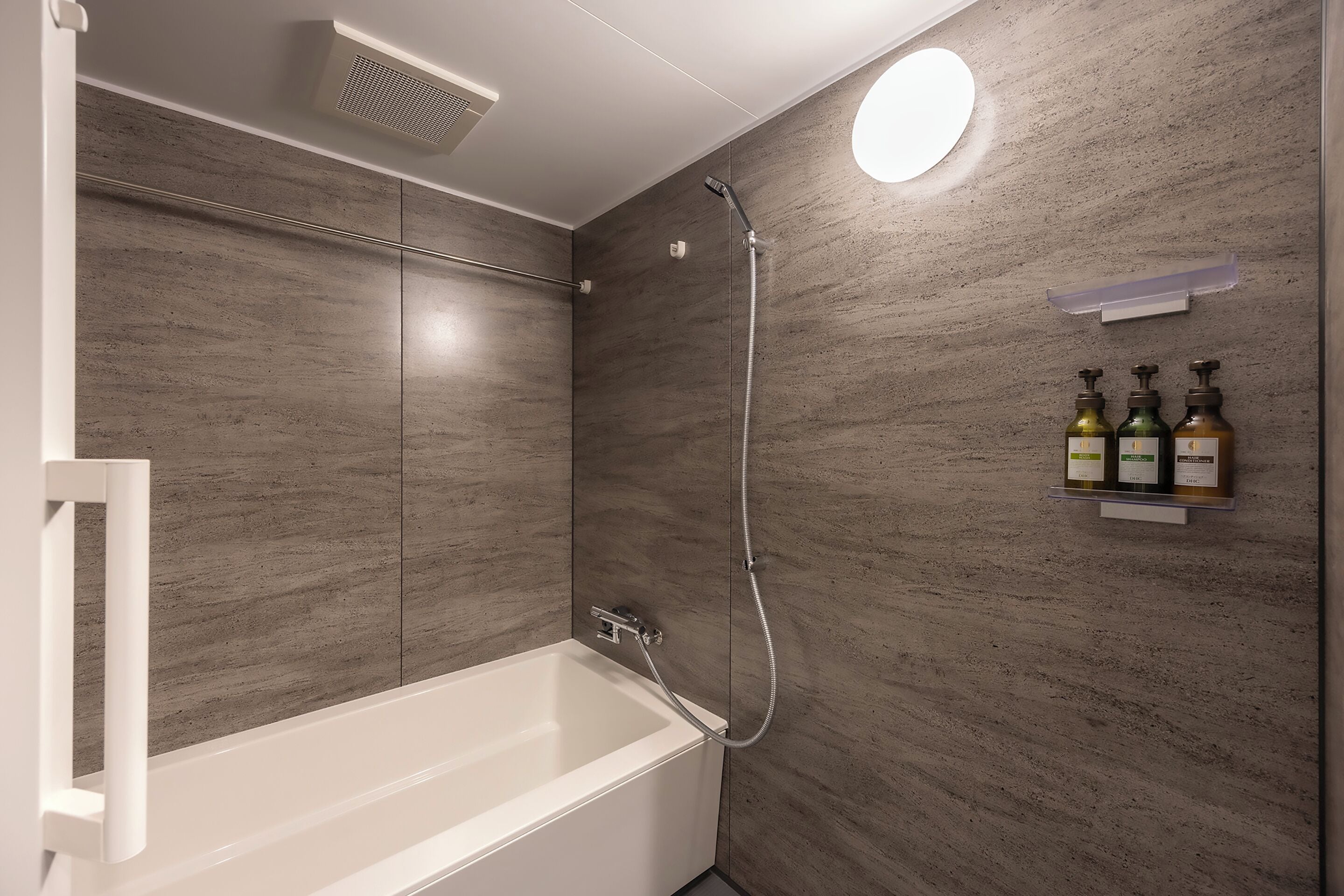 A modern bathroom with a bathtub, a shower, and a wall-mounted shelf with toiletries.