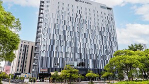 A modern hotel building with a grid-like facade, balconies, and a sign for 'KOKO HOTEL.'
