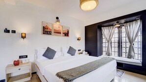 A bedroom with a bed, bedside tables, wall-mounted lamps, a window with curtains, and framed pictures on the wall. - Alaya Stays Cleft 3BHK with Garden (Kotagiri)